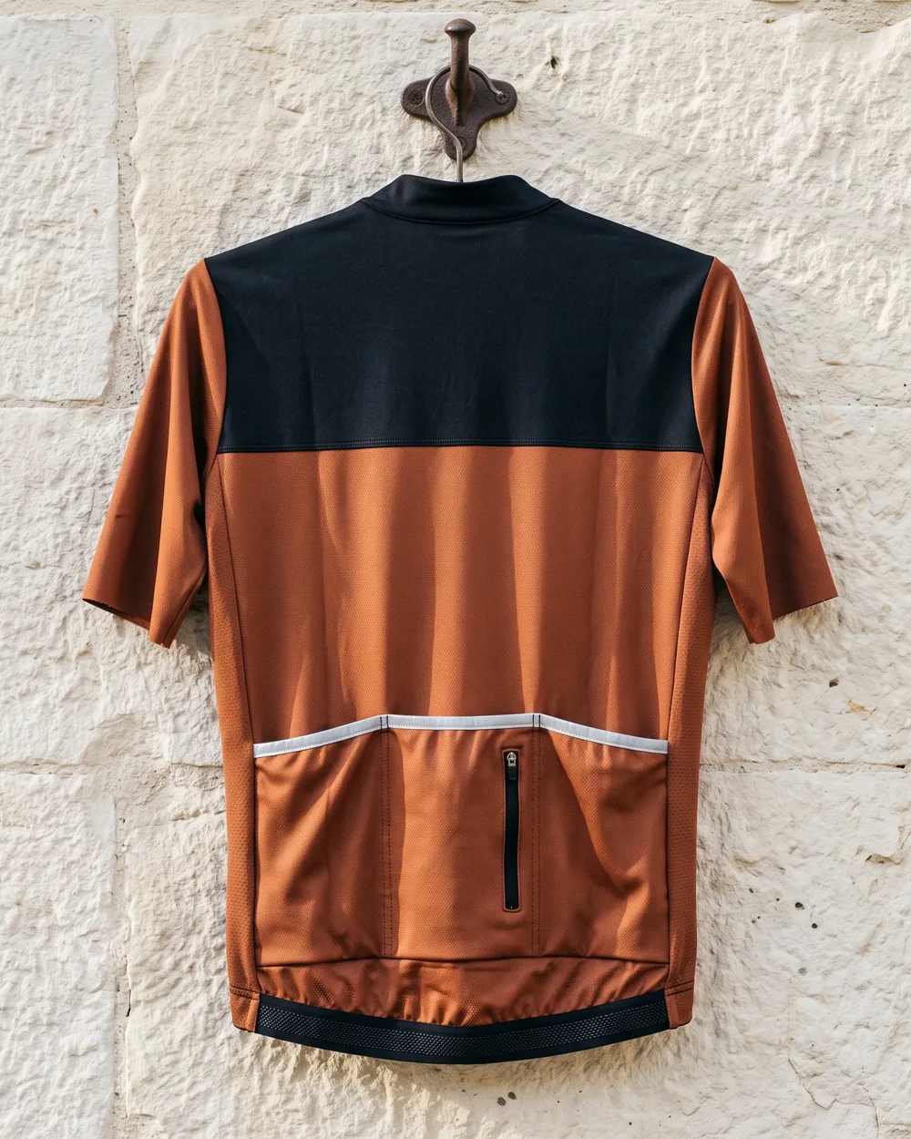 Back of a team jersey showing three rear pockets with a zipped pocket, a silicone gripper hem, a reflective strip at the pocket opening and laser-cut sleeve ends
